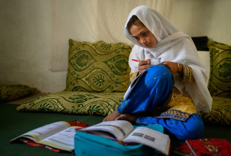 O imagine care înfățișează o fată afgană studiind, desemnată Fotografia Anului 2025 de UNICEF